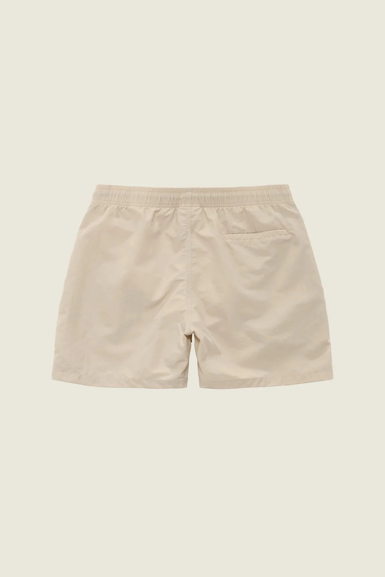 Back view of beige swim shorts on a light background