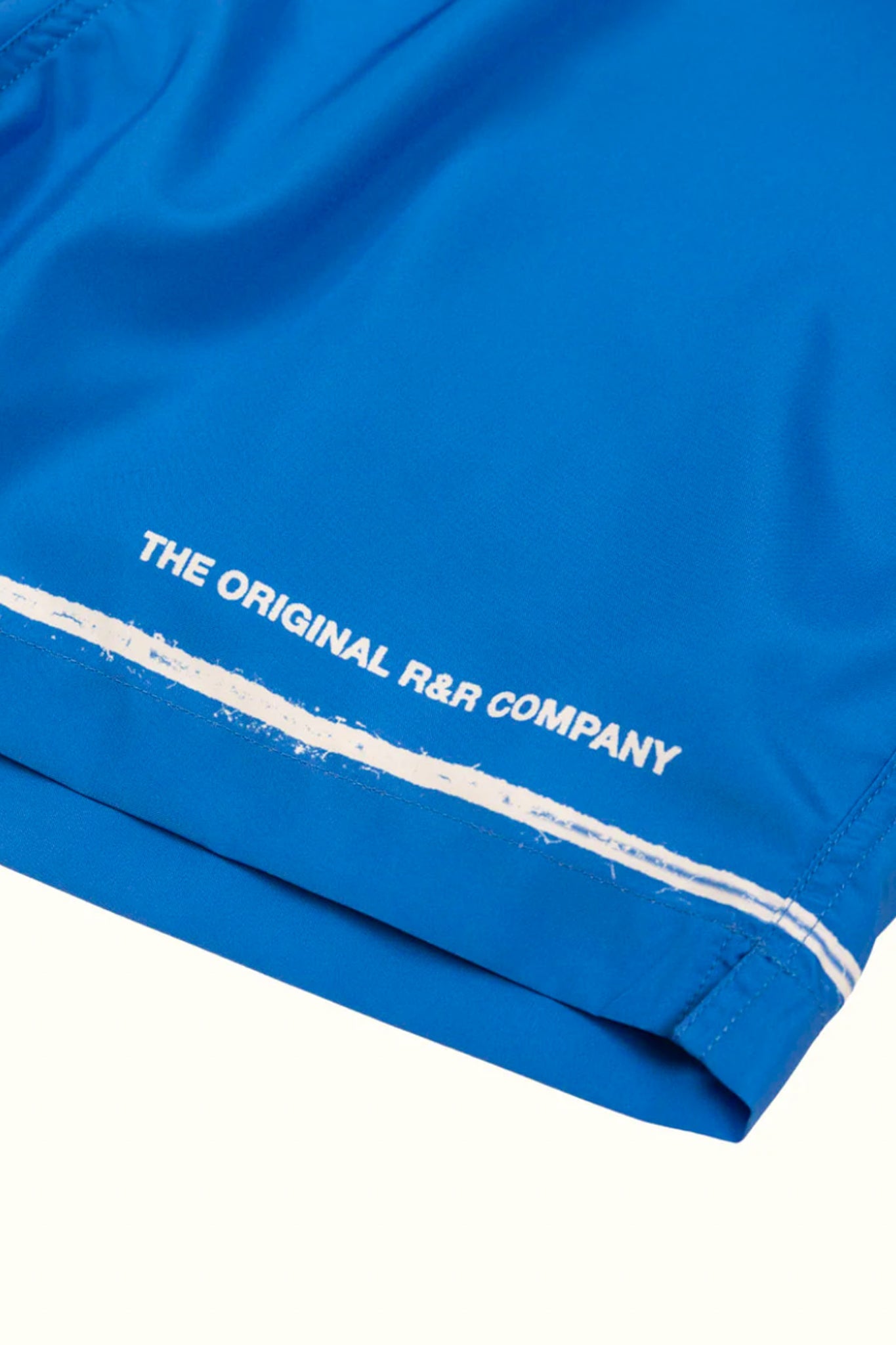 Close-up of blue fabric with 'The Original R&R Company' text in white.