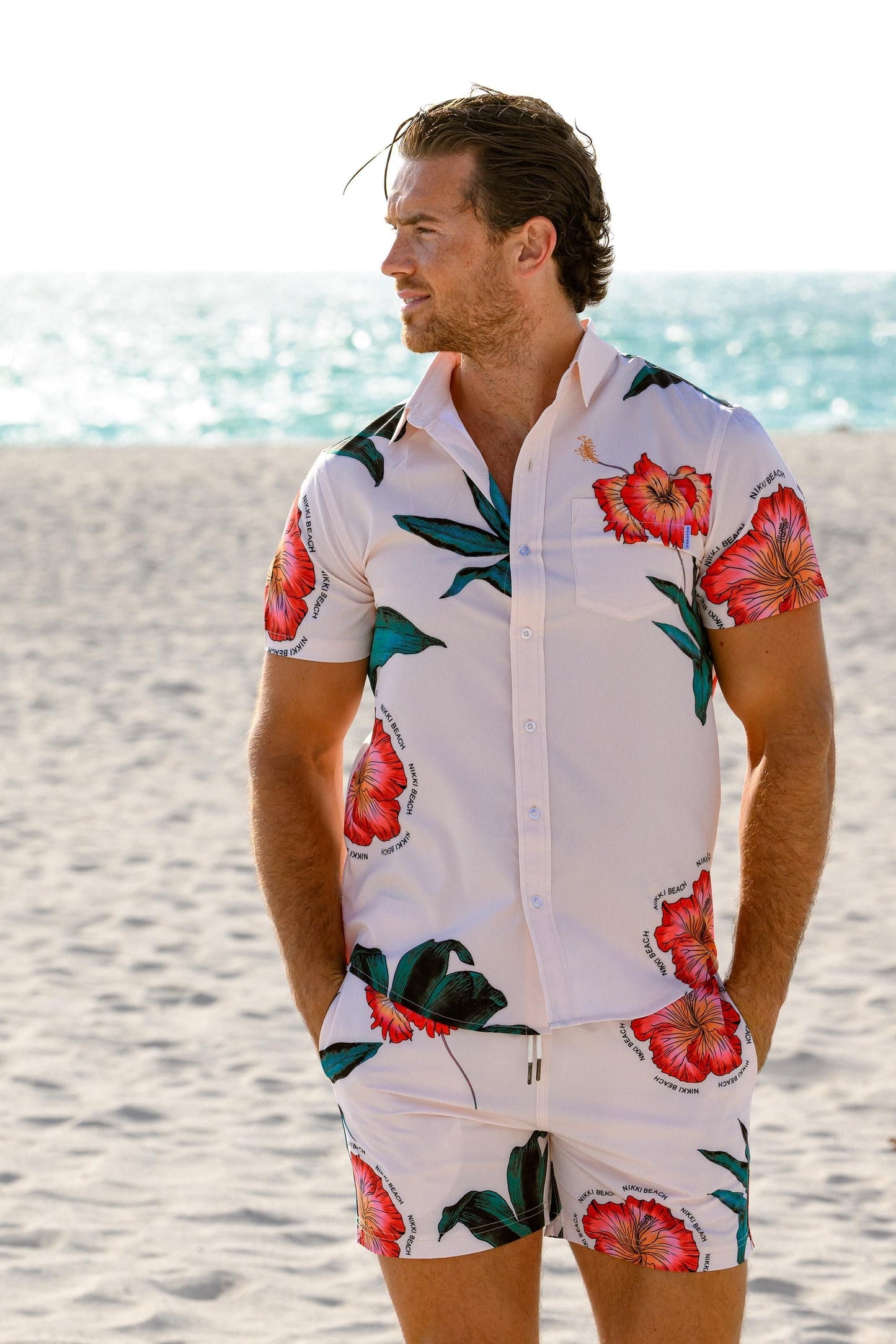 Man in floral shirt and shorts on the beach